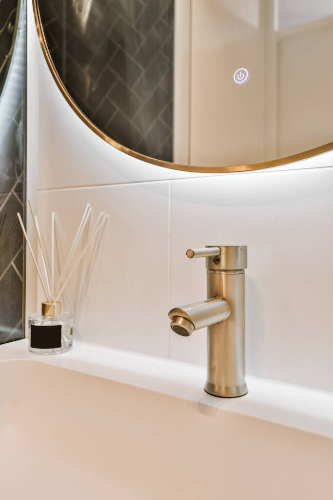 a white sink with a gold faucet