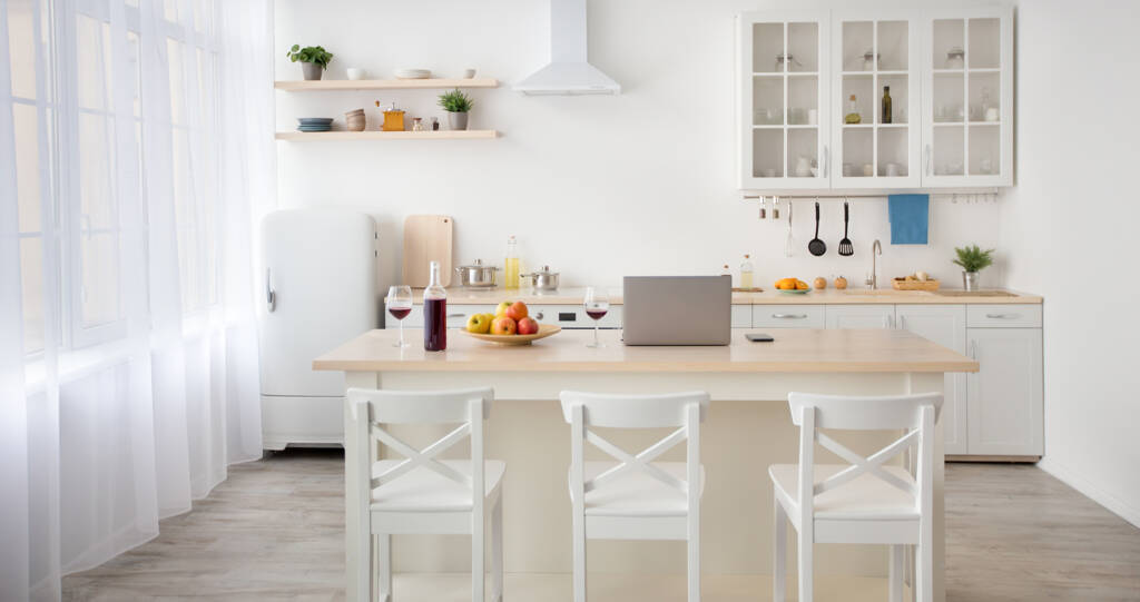 a white kitchen with a laptop on the table