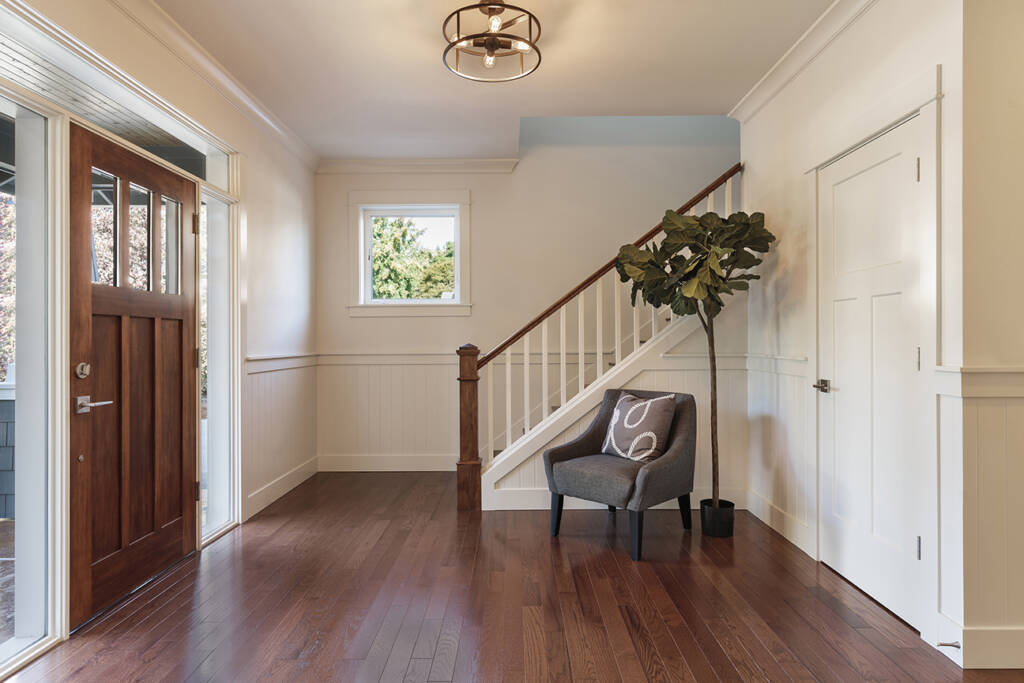 An entryway with hardwood floors and a chair.